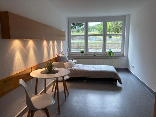 a bedroom with a bed and a table and two windows at Gemütliche Monteurswohnungen voll möbliert & Zentral in Nentershausen