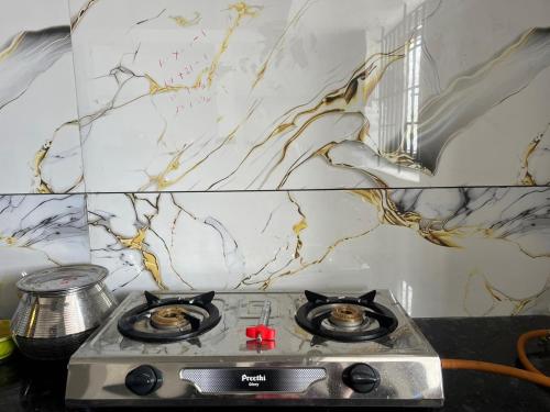 a kitchen with a stove top with a marble wall at AC 3BHK premium house in Pollāchi