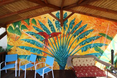 a mural on a wall with chairs and a couch at Hotel La Maison Creole in Le Gosier