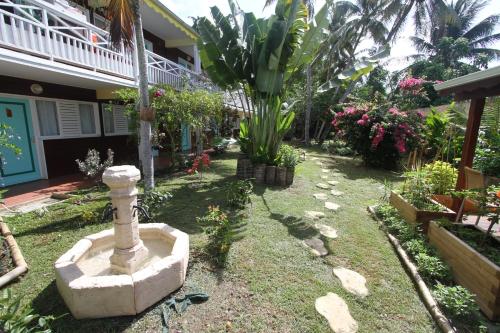 a garden in front of a house with a fountain at Hotel La Maison Creole in Le Gosier