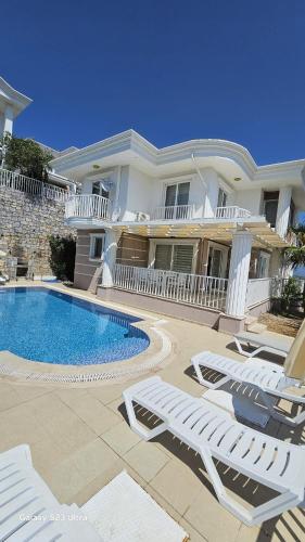 a large house with a swimming pool and lounge chairs at Villa Rana The Royal Links Sarigerme in Ortaca