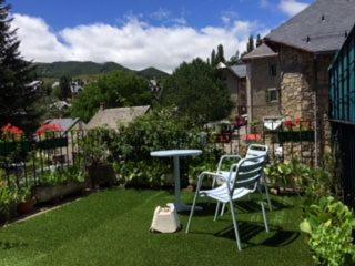 a patio with two chairs and a table in the grass at Hotel Boutique Balaitus in Sallent de Gállego