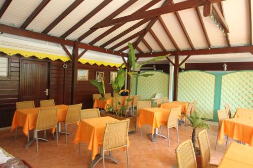 a restaurant with orange tables and chairs in a room at Hotel La Maison Creole in Le Gosier