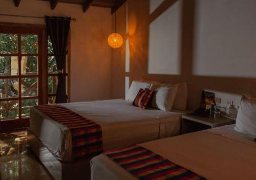 a bedroom with two beds and a window at Hotel & Mariposario Mayan Hills Resort in Copan Ruinas