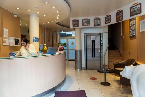 a woman talking on a cell phone in a lobby at Hotel Ours Blanc - Victor Hugo in Toulouse