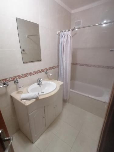 a white bathroom with a sink and a shower at Casa do Quebrado in Peniche