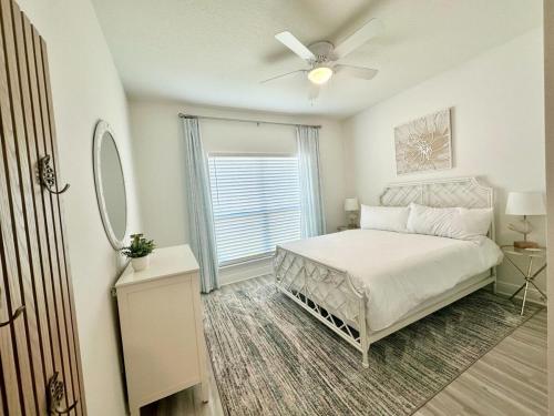 Un dormitorio con una cama con ventilador de techo y una ventana. en The Sandpiper Hideaway - Community Pool, en Santa Rosa Beach