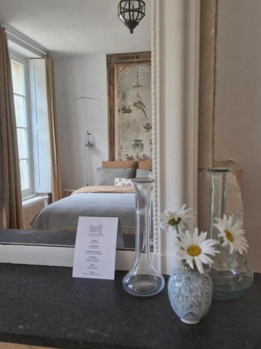 a bedroom with a bed and two vases on a counter at La Maison Pelloquin in Bernières-sur-Mer