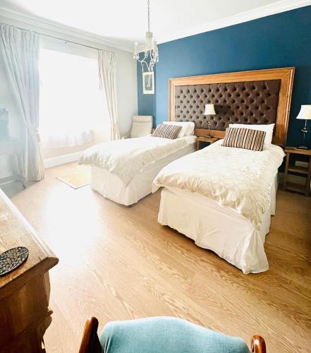 a bedroom with two beds and a blue wall at Ascot House Hotel in Torquay