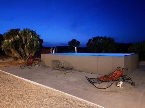 two chairs and a dog sitting on a patio at night at Country house pura natura Alghero in Casa Minnina