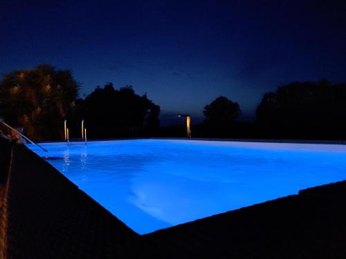 a large blue swimming pool at night at Country house pura natura Alghero in Casa Minnina