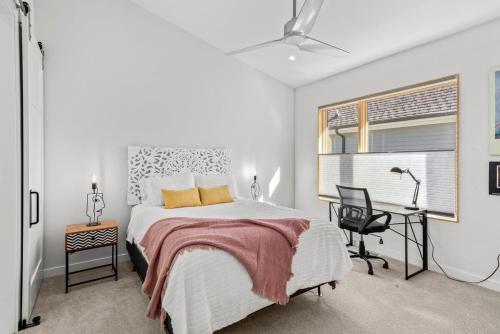 a white bedroom with a bed and a desk at Luxury Downtown Townhome - 120 Theater & Patio in Bentonville