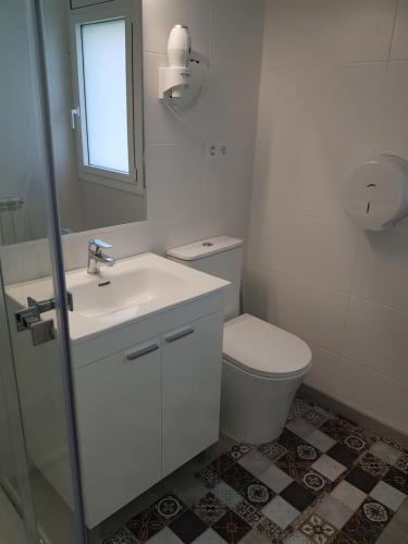 a white bathroom with a toilet and a sink at Habitacion en alojamiento turistico compartido con la amfitriona, estancias compartidas baño, terraza, cocina in Vilanova de Sau