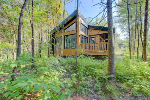 una casa nel bosco con un portico perimetrale di Chalet Le Baikal a Pont-Rouge