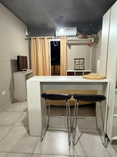 une cuisine avec un comptoir blanc et deux tabourets de bar dans l'établissement CHINO I, à San Miguel de Tucumán