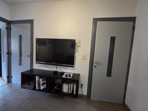 un salon avec une télévision à écran plat sur un mur dans l'établissement Bel-étage cosy 2 chambres proche Charleroi-Airport, à Charleroi