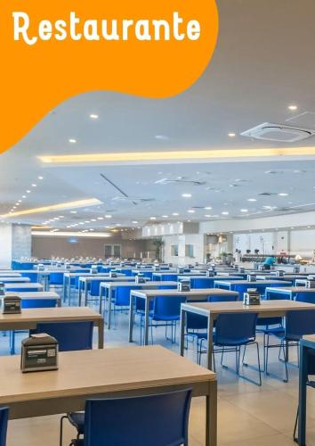 eine leere Cafeteria mit Tischen und blauen Stühlen in der Unterkunft Solar das Aguas Resort in Olímpia