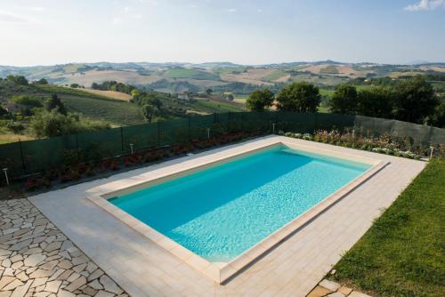 a swimming pool in a garden with a view of the hills at B&B Montechiaro in Mogliano