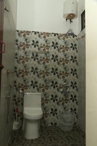 a bathroom with a toilet and a floral tile wall at L'EDELWEISS Heritage House in Puducherry