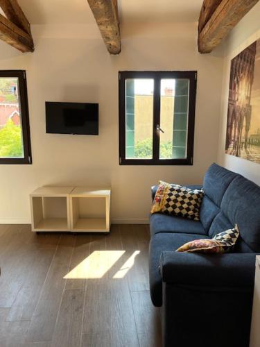 a living room with a blue couch and a tv at Casa sulla Laguna CASTELLO in Venice
