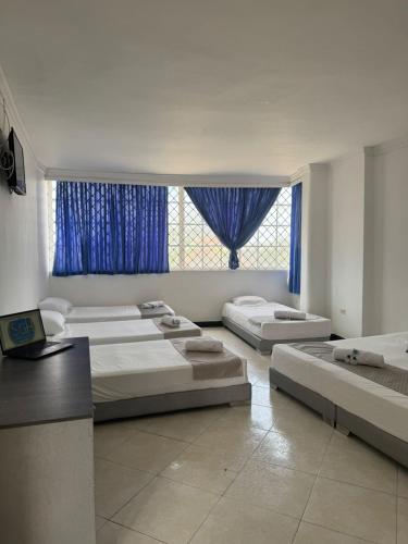 a room with four beds and a window with blue curtains at SGH Castillo Aqua in Santa Marta