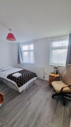 a bedroom with a bed and a chair at Panthea Home in Barkingside