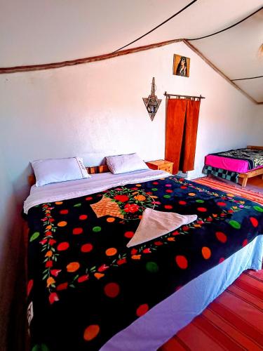 a bedroom with a large bed with a colorful comforter at The dune camp in Mhamid