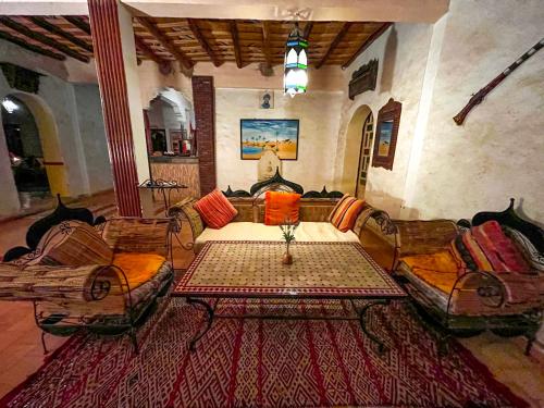 a living room with a couch and a table and chairs at Kasbah Erg Chebbi in Merzouga