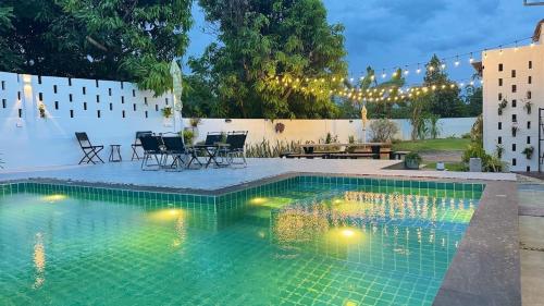 a swimming pool with a table and chairs in a backyard at Vela Pool Villa Hatyai in Sathani Khlong Rian