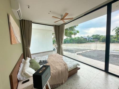 a bedroom with a bed and a large glass window at Phú Xuân Homestay - Gần Dốc Hoàng Hôn, Phòng Rộng View Sông in Phan Thiet