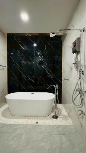 a bath tub in a bathroom with a black wall at Vela Pool Villa Hatyai in Sathani Khlong Rian