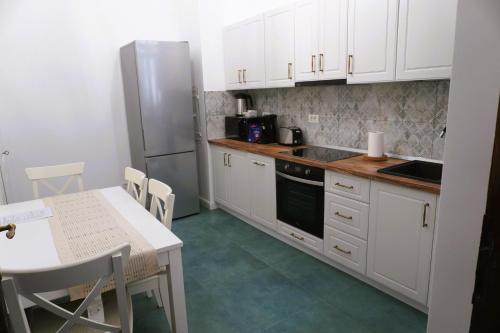 a kitchen with white cabinets and a table and a refrigerator at Sibla Residence, Unique Experience Heritage House in Lugoj