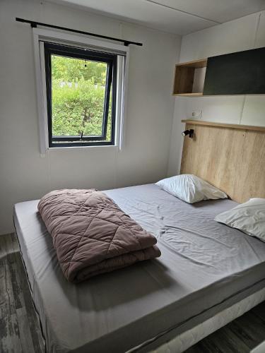 a bedroom with a large bed with a window at Mobilhomme Privilège in Biscarrosse