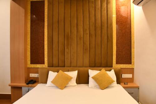 a bedroom with a white bed with yellow pillows at Hotel Golden Continental in Deoghar