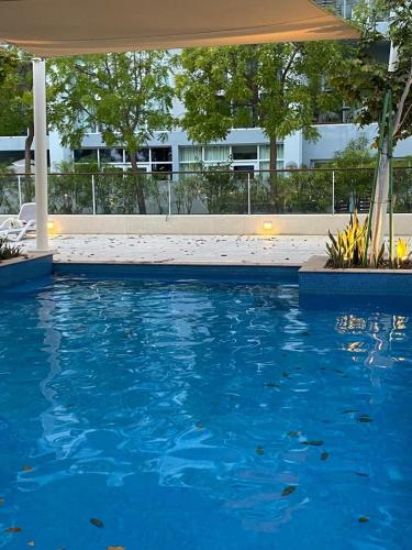 a swimming pool with an umbrella and blue water at Al Mouj Marina Apartment with Pool & Beach Access in Ḩayl Āl ‘Umayr
