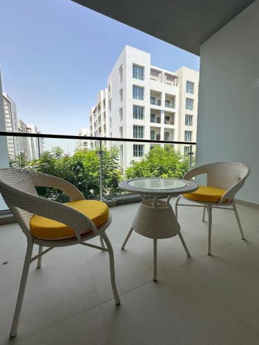 a balcony with two chairs and a glass table and chairs at Al Mouj Marina Apartment with Pool & Beach Access in Ḩayl Āl ‘Umayr