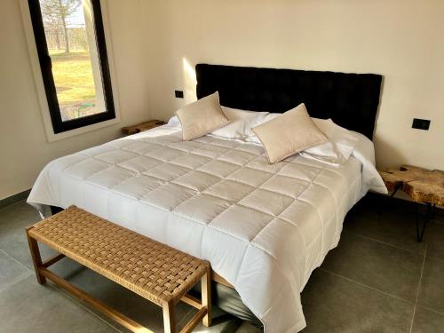 a large white bed with a bench in a room at Finca Torcivia Luna in Vista Flores