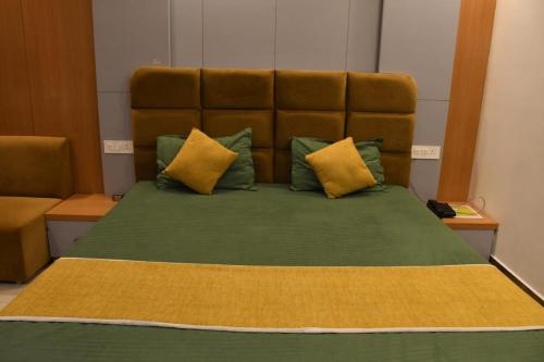 a large bed with green sheets and yellow pillows at Hotel Golden Continental in Deoghar