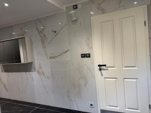 a bathroom with white marble walls and a white door at Résidence des Fleurs in Hombourg-Haut