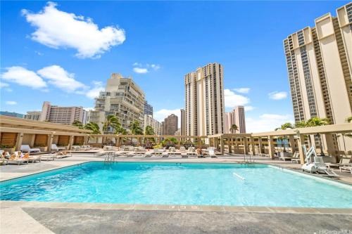 a large swimming pool with lounge chairs and buildings at Top Floor Studio with Balcony & Views 3528 in Honolulu