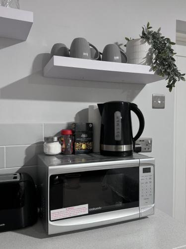 a microwave with a coffee pot on top of it at studio flat near NEC, Solihull & Airport. Short & Long stay Contractors HS2, NHS in Solihull