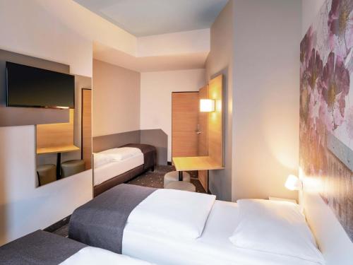 a hotel room with two beds and a tv at B&B Hotel Hildesheim in Hildesheim