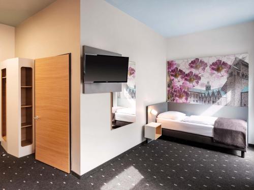 a room with a bedroom with two beds and a tv at B&B Hotel Hildesheim in Hildesheim