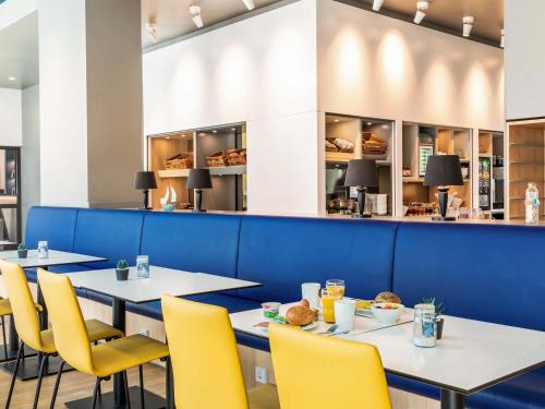 a row of tables in a restaurant with yellow chairs at B&B Hotel Hamburg City-Ost in Hamburg