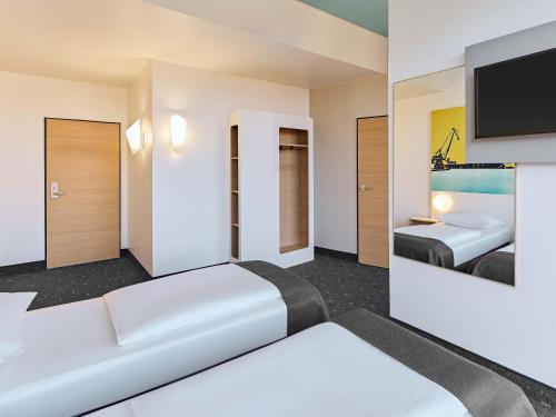a hotel room with two beds and a flat screen tv at B&B HOTEL Münster Hafen in Münster