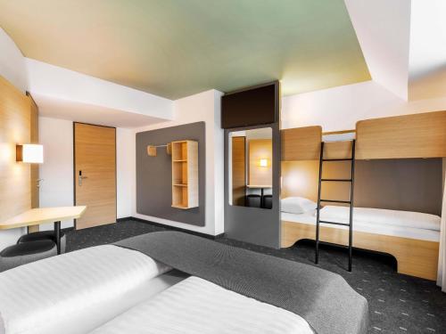 a bedroom with two bunk beds and a desk at B&B HOTEL Wien-St-Marx in Vienna