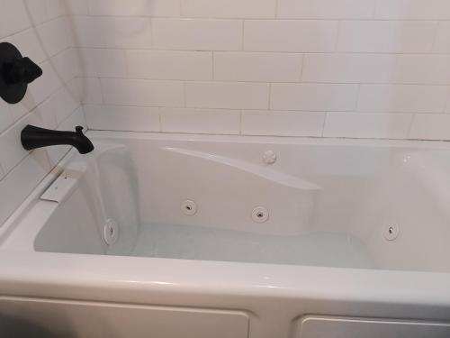 a white bath tub with a black faucet in a bathroom at Pensacola hidden gem cottage 3 minutes from Navy Base, pet friendly in Pensacola