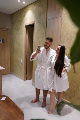 a man and woman in white robes taking a picture in a bathroom at FR Hotel in Ibagué