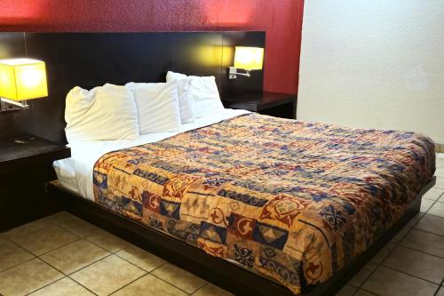 a bed in a hotel room with two tables and two lamps at River Valley Inn and Suites in Fort Smith