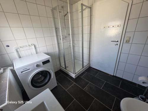 a bathroom with a washing machine and a shower at MaiFerien Harz - Haus Goldstrahl in Clausthal-Zellerfeld